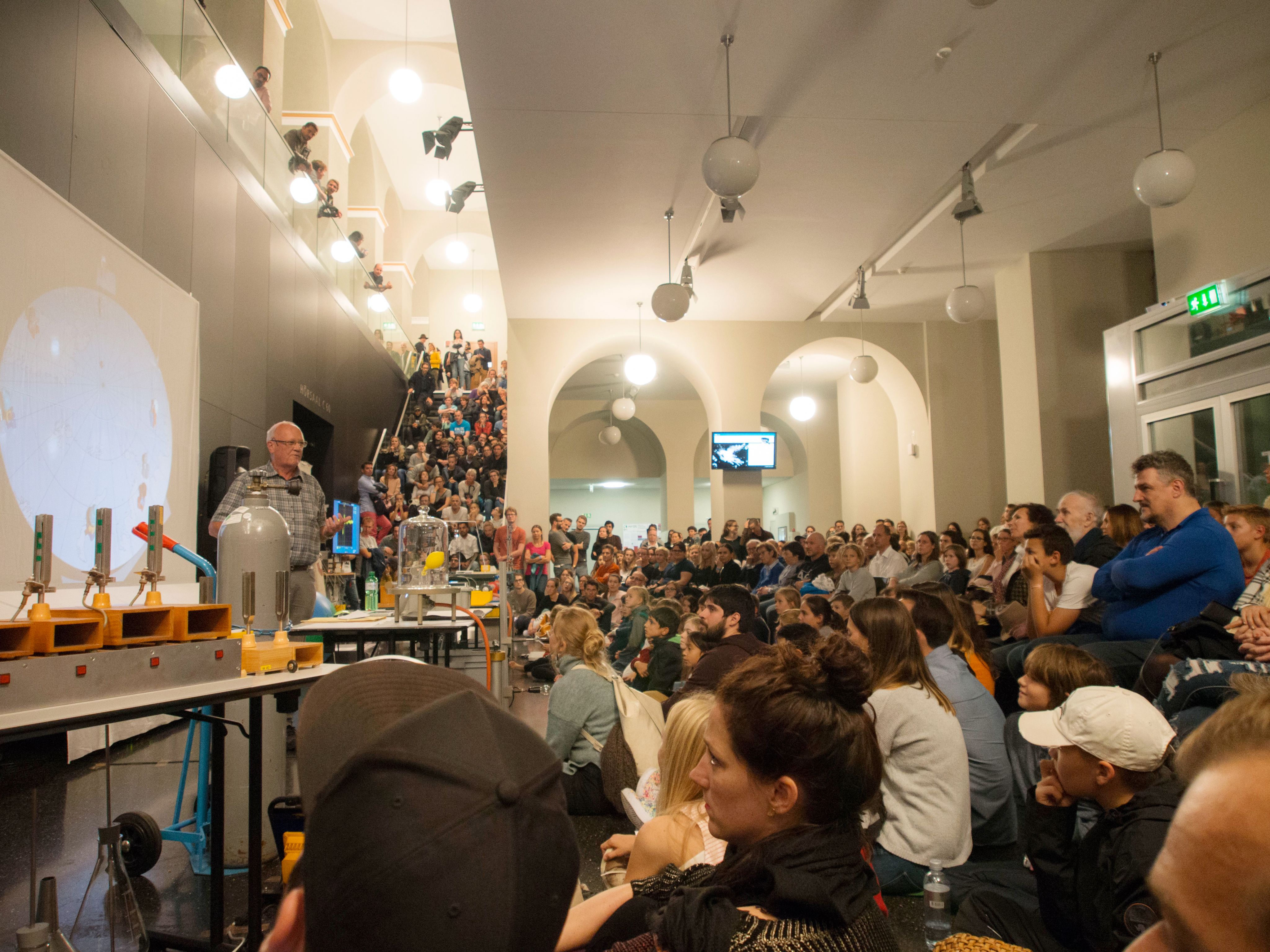 Zahlreiche Zuschauer folgen fasziniert einer Physik-Show.