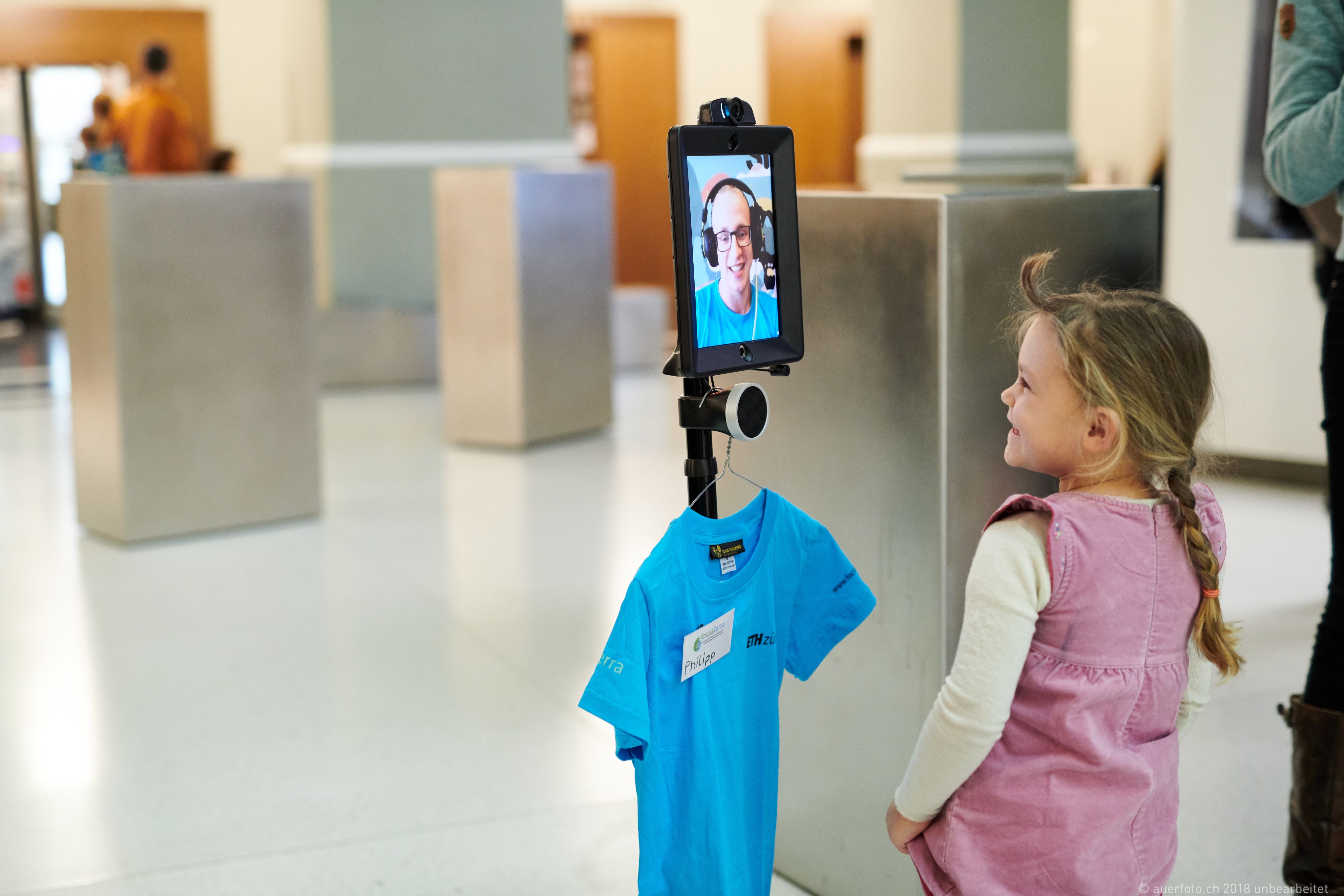 Mädchen unterhält sich mit einem Guide, der am Bildschirm eines Roboter mit ihr spricht.